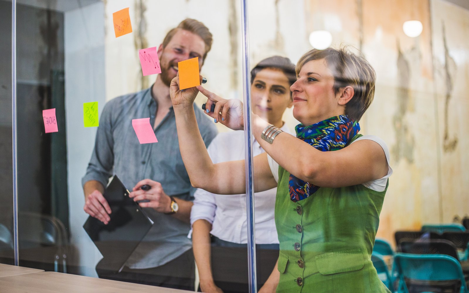 Teilnehmer/-innen eins Workshops schreiben Zettel, die sie an eine Glaswand heften.