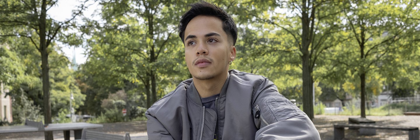 Ein Schüler sitzt im Park auf einer Tischtennisplatte.