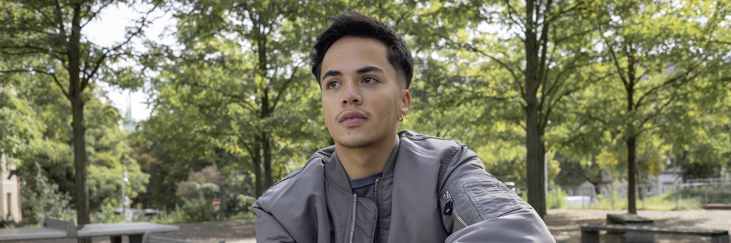 Ein Schüler sitzt im Park auf einer Tischtennisplatte.