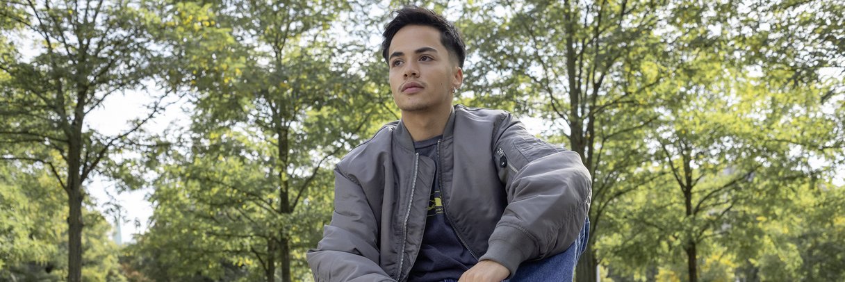 Ein Schüler sitzt im Park auf einer Tischtennisplatte.