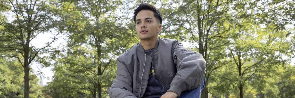 Ein Schüler sitzt im Park auf einer Tischtennisplatte.