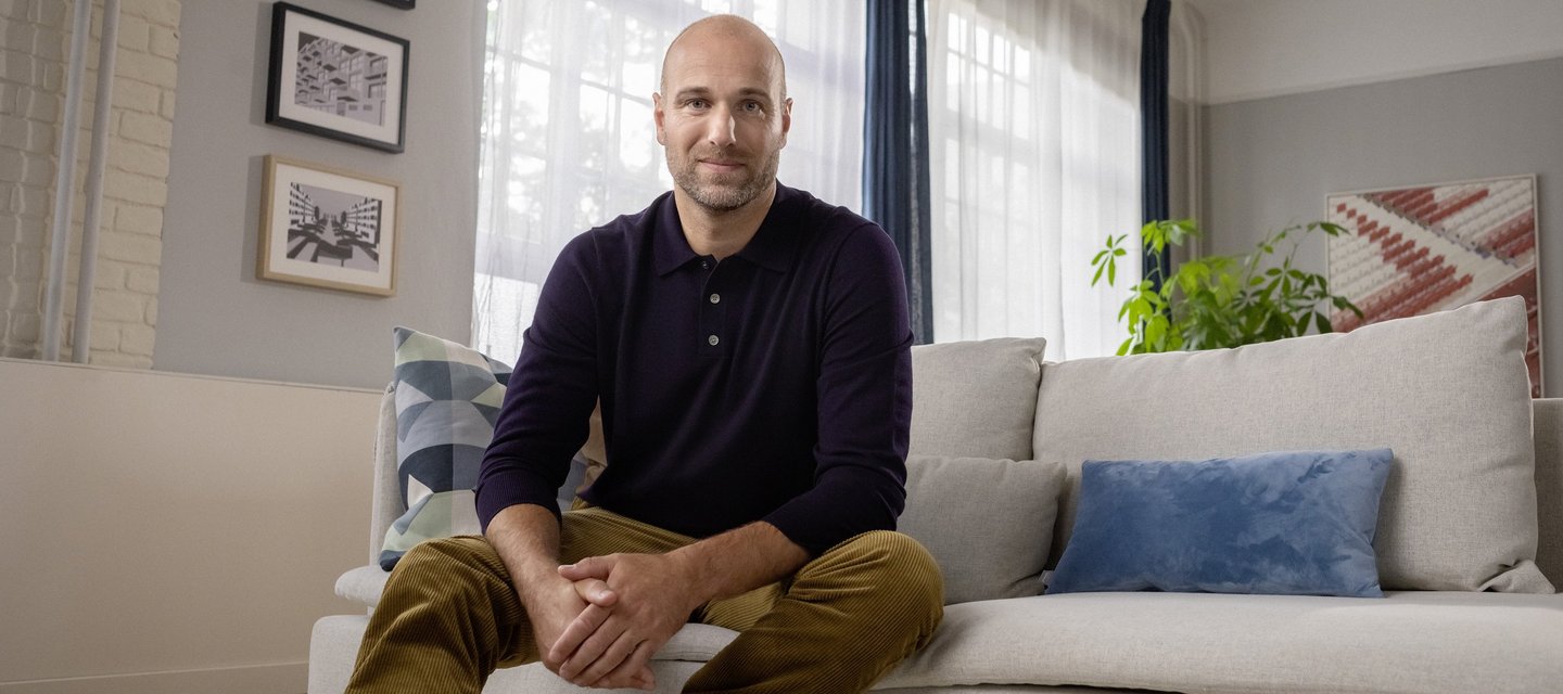 Ein berufserfahrener Mann sitzt auf der Couch in seinem Wohnzimmer.