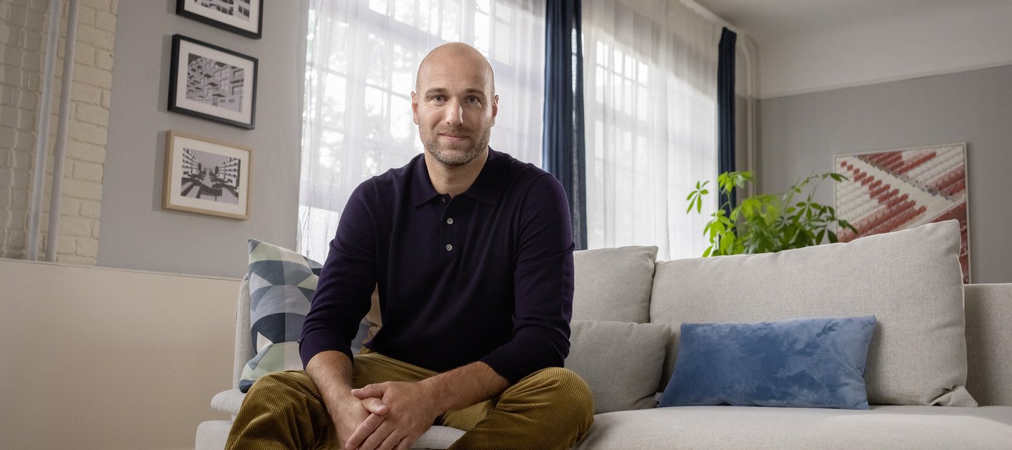 Ein berufserfahrener Mann sitzt auf der Couch in seinem Wohnzimmer.