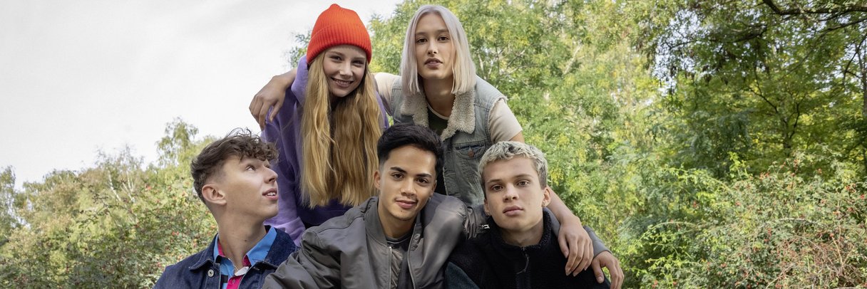 Eine Clique von Schülerinnen und Schülern posiert im Park für ein Foto.