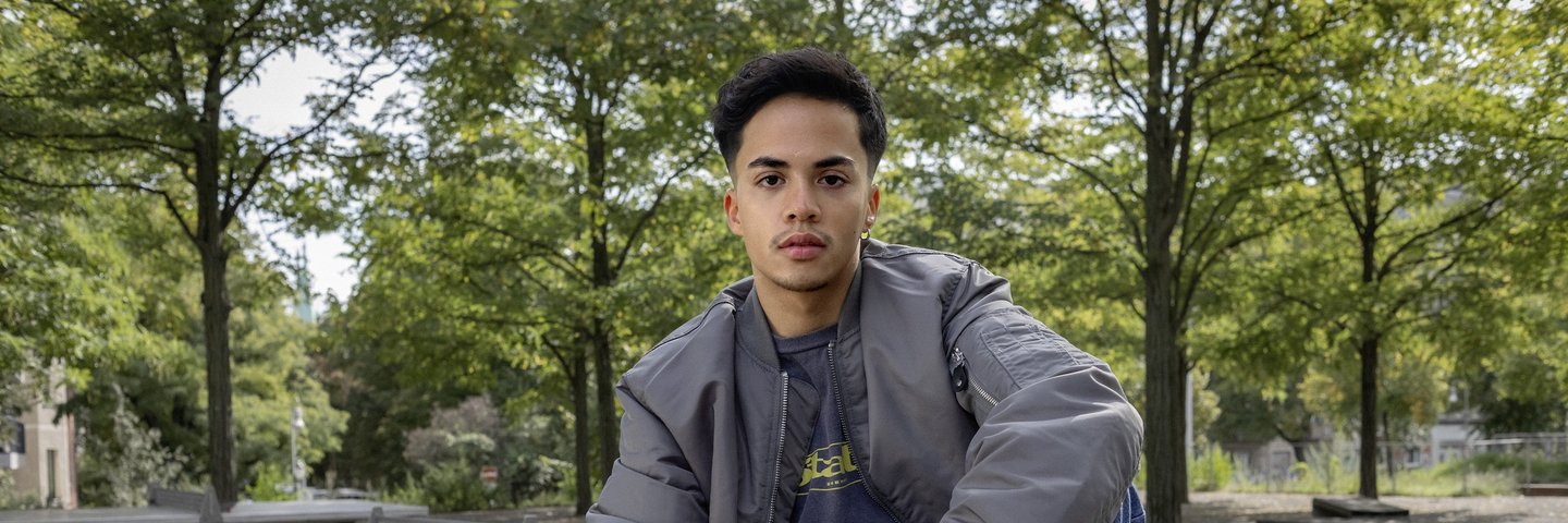 Ein Schüler sitzt im Park auf einer Tischtennisplatte.