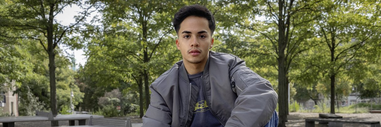 Ein Schüler sitzt im Park auf einer Tischtennisplatte.