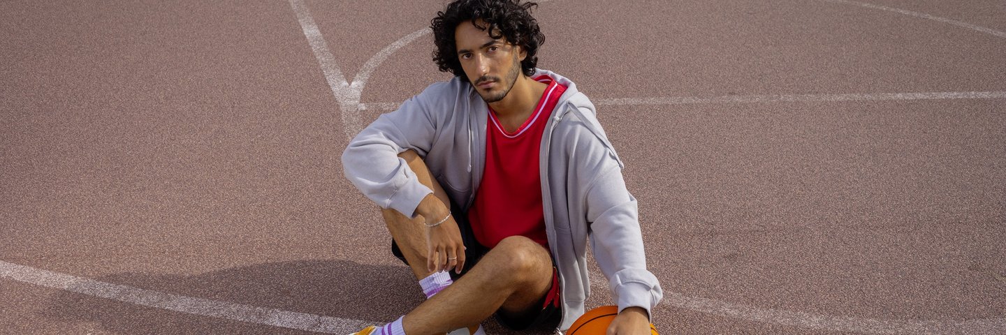 Ein Student sitzt auf einem Basketballfeld.