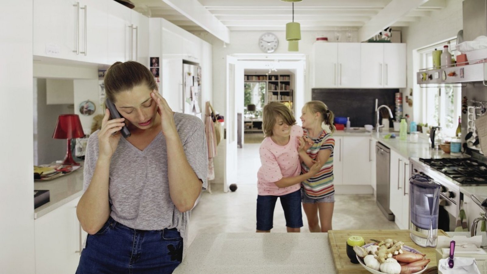 Eine Frau telefoniert während im Hintergrund Kinder streiten.