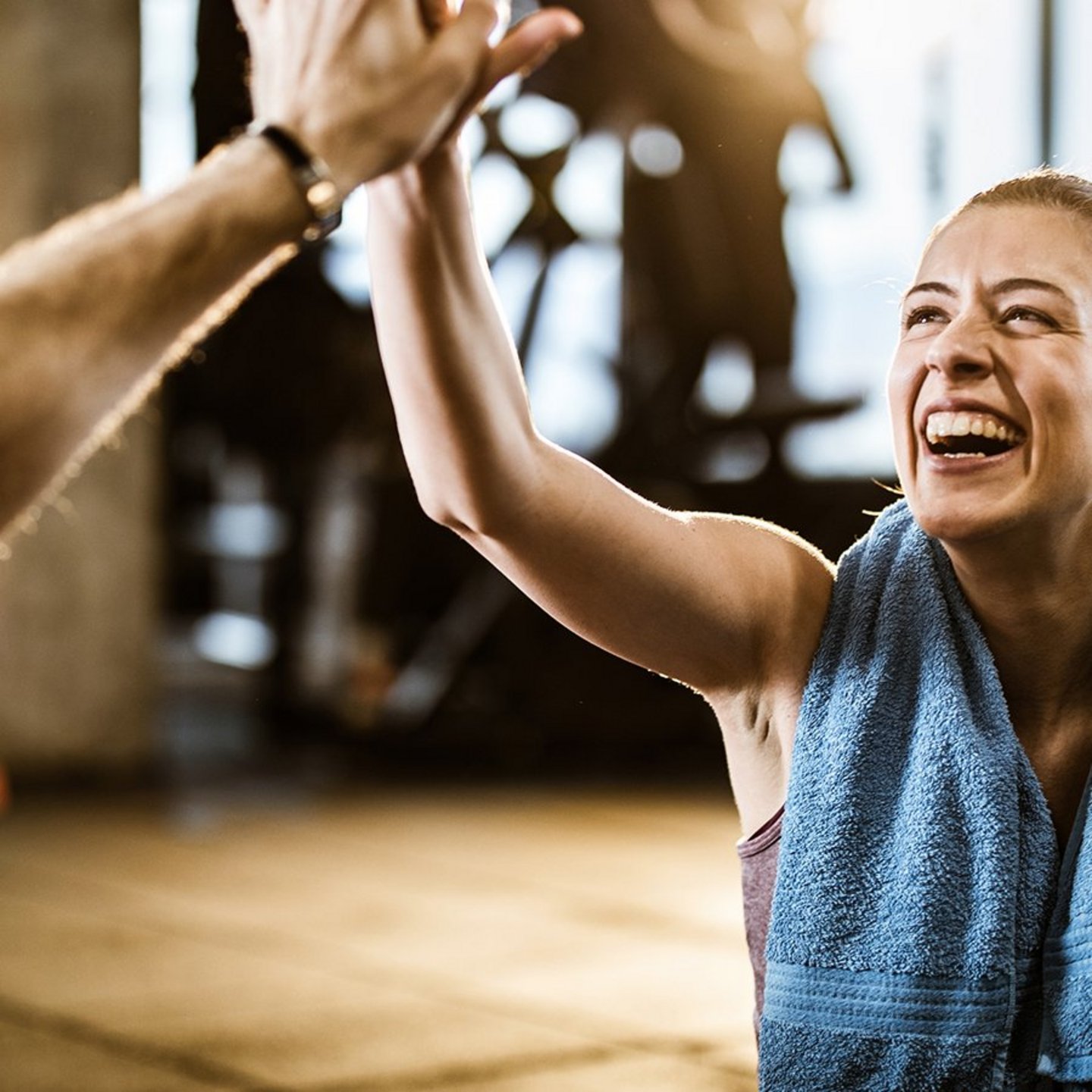Eine glückliche Sportlerin gibt ihrem Trainingspartner in einem Fitnessstudio einen High-Five.