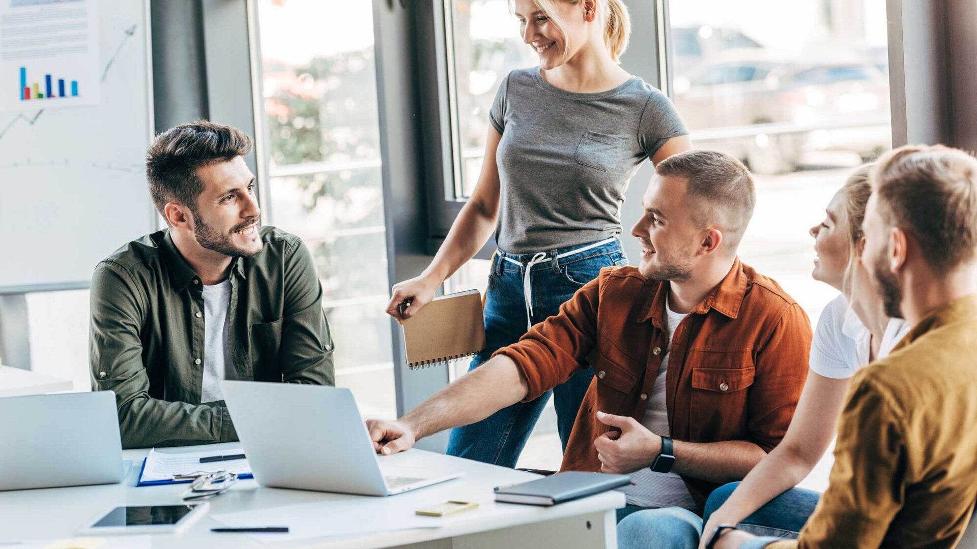 Junge Mitarbeiter eines Startups besprechen sich in lockerer Runde im Büro