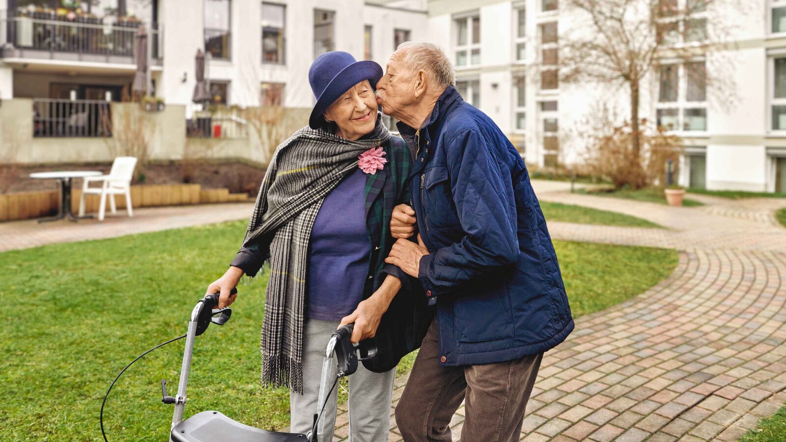 Ältere Frau mit Rollator wird liebevoll gestützt – Symbolbild für Pflege
