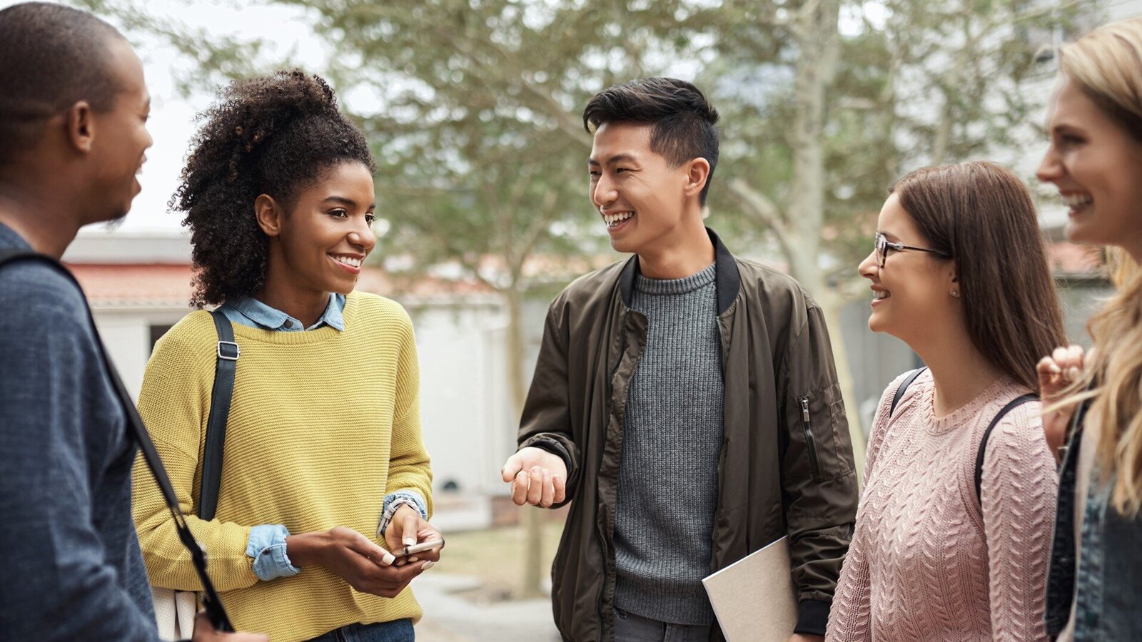 Eine lächelnde Gruppe junger Personen steht zusammen im Halbkreis