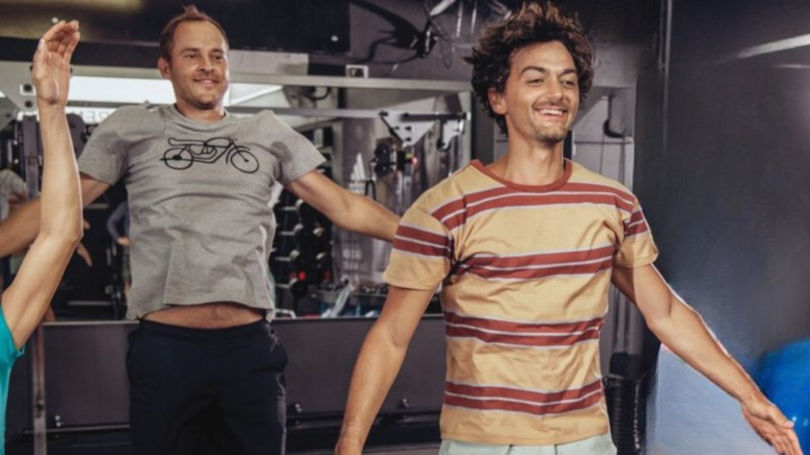 Zwei Männer springen im Fitnessstudio in die Luft.