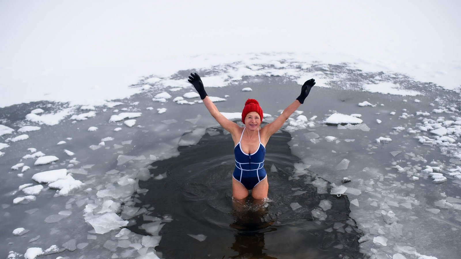 Aktive Seniorin im Badeanzug beim Eisbaden, Konzept der Kältetherapie.