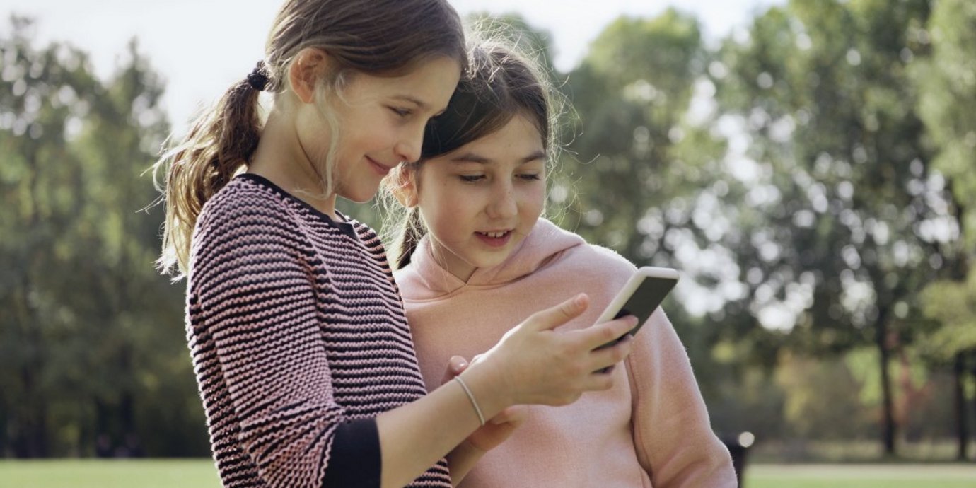Zwei Kinder schauen in ein Smartphone.