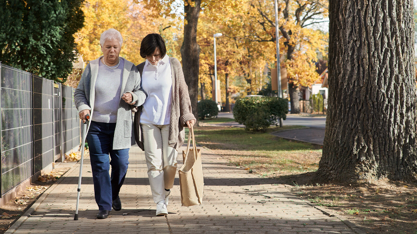 Eine ältere Dame geht mit einer Frau spazieren. 