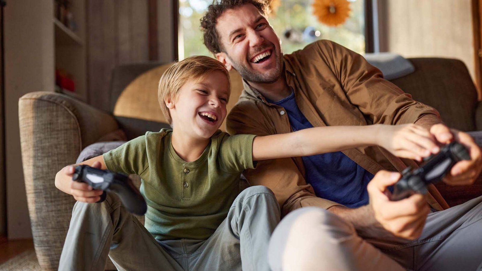 Fröhlicher Vater und Sohn spielen zu Hause Videospiele.