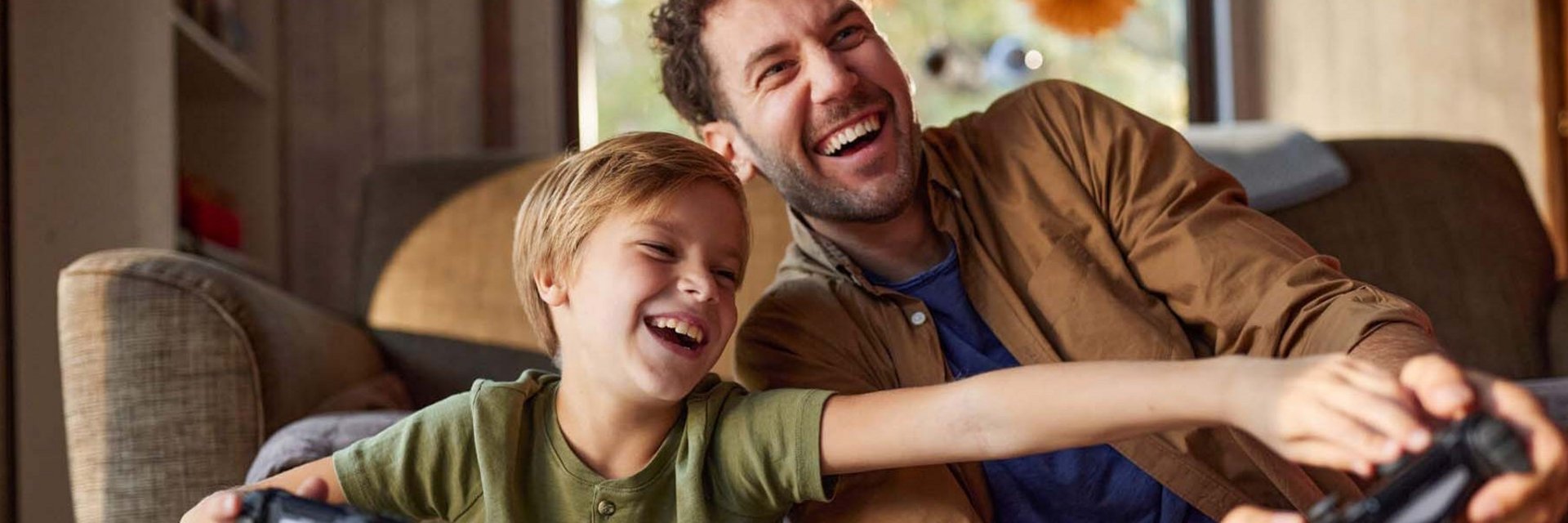 Fröhlicher Vater und Sohn spielen zu Hause Videospiele.