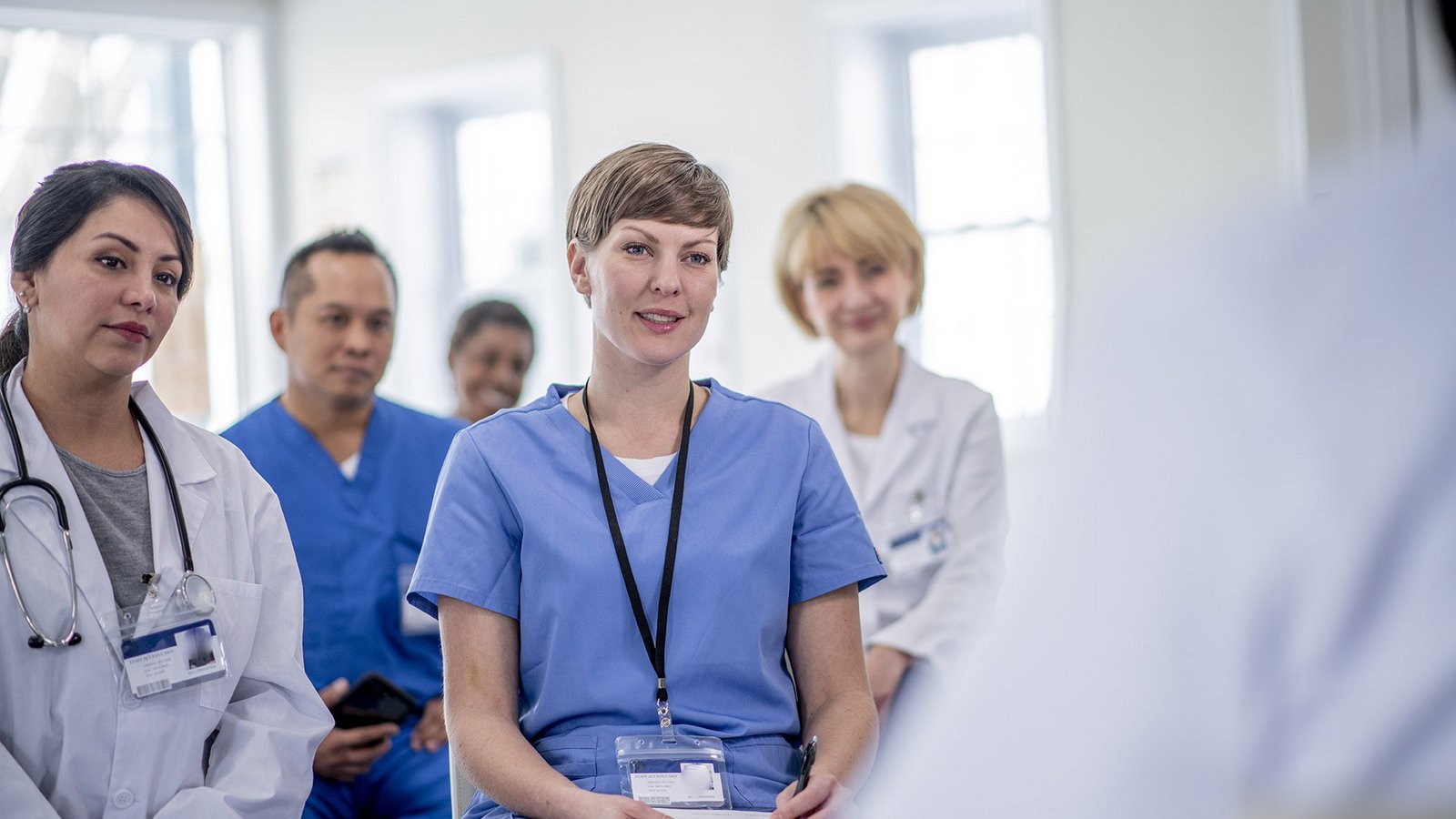 Eine Gruppe von Pflegekräften sitzt vor einer vortragenden Person. 