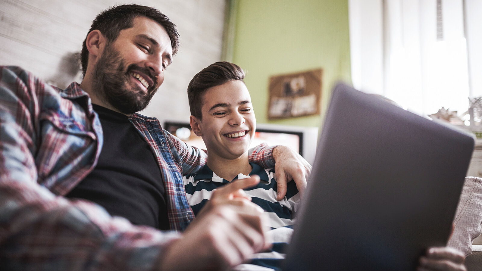 Vater und Sohn sitzen lachend vor einem Laptop
