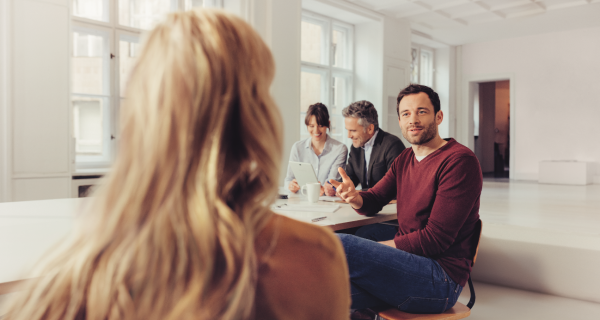 Zwei Frauen und zwei Männer sitzen an einem Tisch zusammen und unterhalten sich in Gruppen