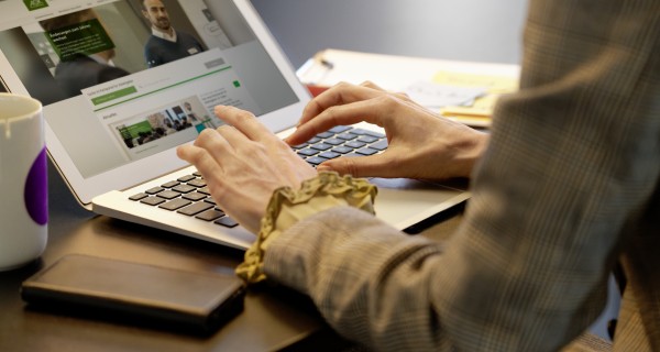 Offener Laptop mit AOK-Website. Die Hände einer Frau tippen auf der Tastatur.