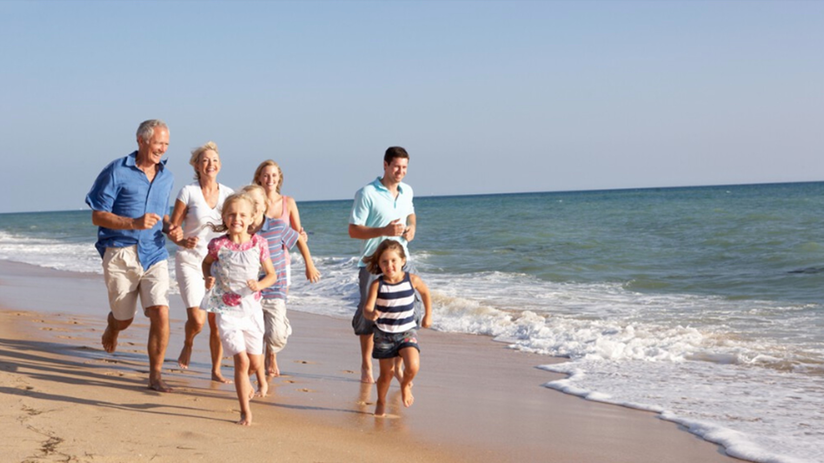 Eine Familie (3 Genration) laufen sportlich an einem Strand ​
​62913514_Familie am Strand_Markenportal