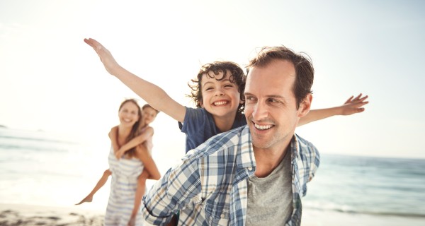 Familie (Eltern / zwei Kinder) haben Spaß im Sommer am Strand