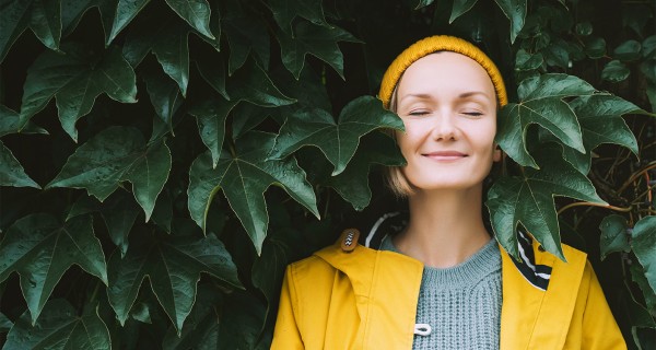 Eine Frau steht an der Hecke und genießt.