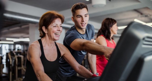 Mann und Frau im Fitnessstudio klatschen sich im Liegestütz die Hände ab.