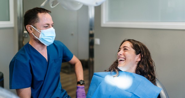 Eine junge Frau sitzt lachend beim Zahnartzt