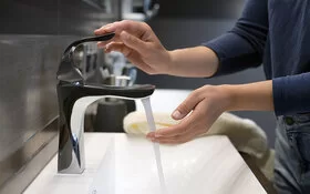 Eine Person spült an einem Waschbecken ihre Hand mit Wasser ab.