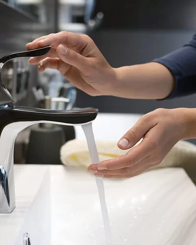 Eine Person spült an einem Waschbecken ihre Hand mit Wasser ab.