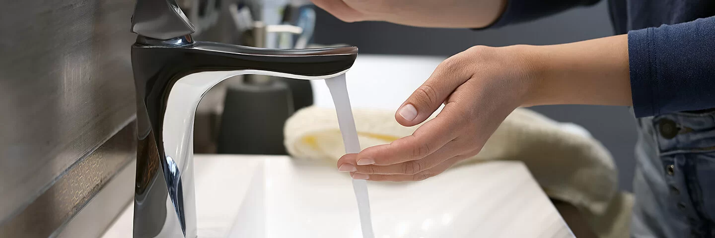 Eine Person spült an einem Waschbecken ihre Hand mit Wasser ab.