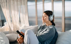 Eine junge Frau betreibt Me-Time und hört Musik mit Kopfhörer.