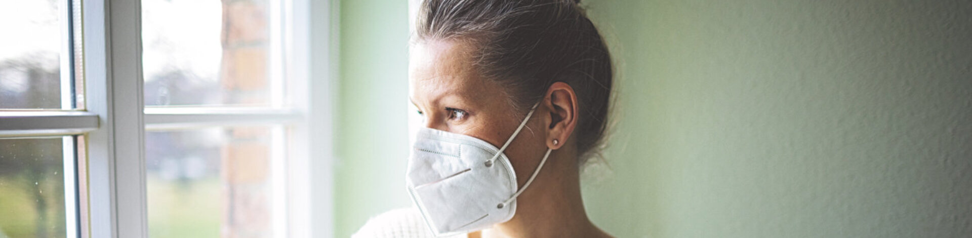 Eine Frau ist zu Hause und trägt eine FFP2-Maske. Erfahren Sie mehr über die Quarantäneregeln während der Corona-Pandemie.