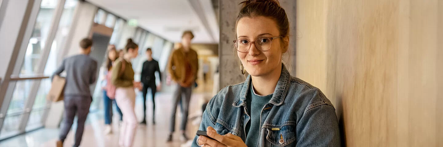 Eine Studentin wartet vor einem Hörsaal. Die AOK sorgt beim Auslandsstudium für den Versicherungsschutz.