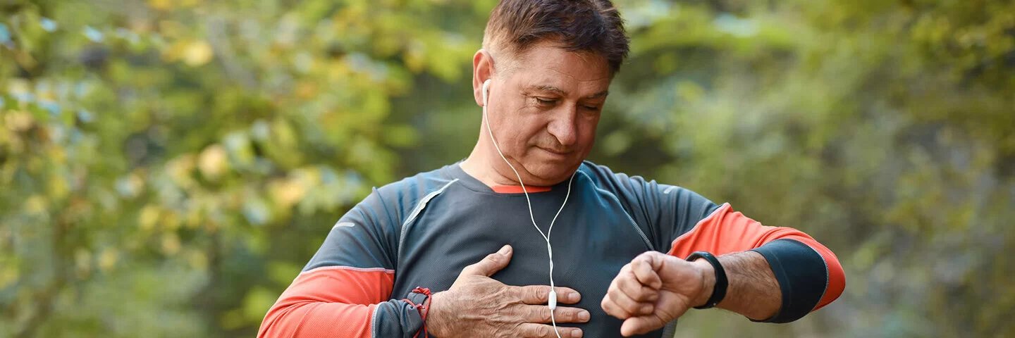 Ein Mann mittleren Alters steht im Freien und überprüft seinen Blutdruck mit einer Smartwatch.