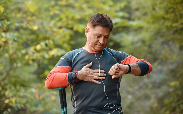 Ein Mann mittleren Alters steht im Freien und überprüft seinen Blutdruck mit einer Smartwatch.