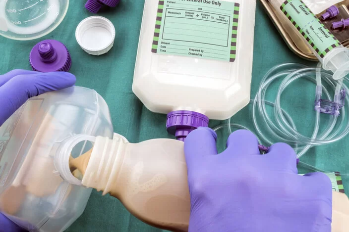 Geräte für die enterale Ernährung liegen auf einem Tisch und werden für die Nutzung vorbereitet.