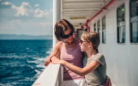Mutter steht mit ihrer seekranken Tochter an der Schiffsreling.
