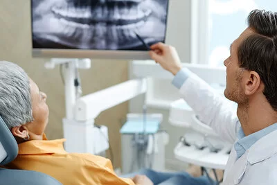 Zahnarzt erklärt einer Patientin die Röntgenaufnahme eines Gebisses.