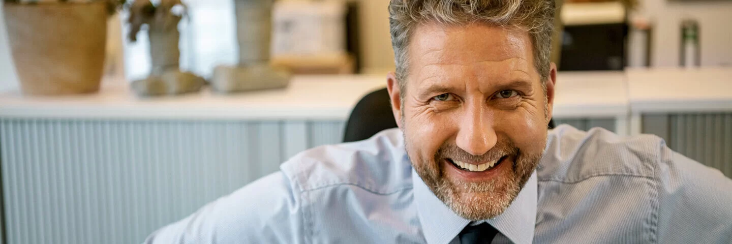 Ein Mann in Hemd und Krawatte lächelt in die Kamera. Als Arbeitgeber weiß er die Vorteile der AOK zu schätzen.
