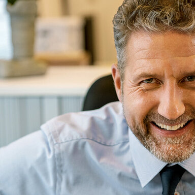 Ein Mann in Hemd und Krawatte lächelt in die Kamera. Als Arbeitgeber weiß er die Vorteile der AOK zu schätzen.