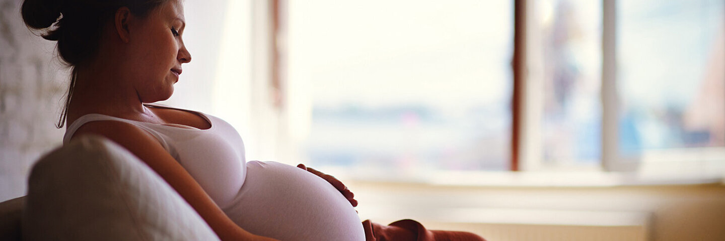 Eine Frau streichelt über ihren Babybauch. Zunehmen ist in der Schwangerschaft ganz normal.