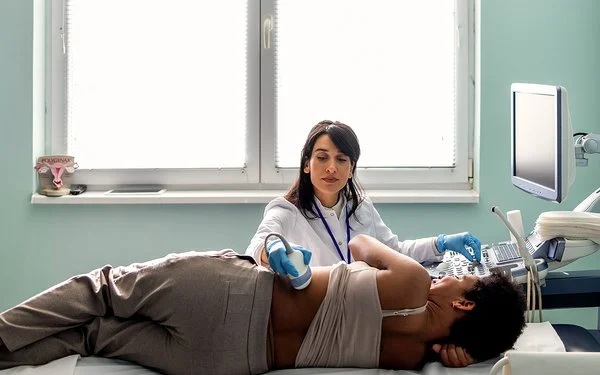 Eine Ärztin macht bei einer jungen Patientin eine Ultraschalluntersuchung der Nieren.
