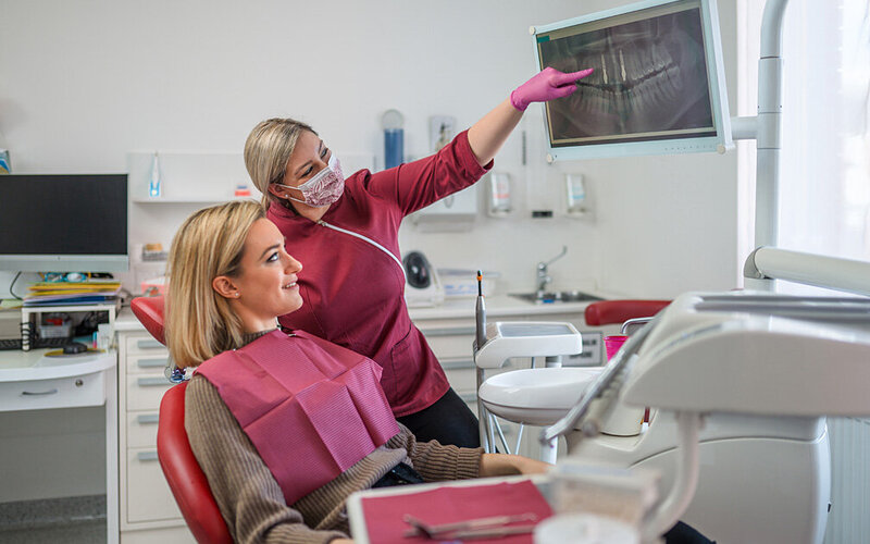 Eine Zahnärztin zeigt einer jungen Frau eine Röntgenaufnahme.
