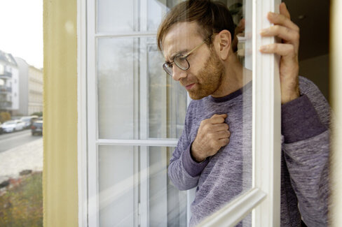 Ein Mann öffnet die Fenster seiner Wohnung. Regelmäßiges Lüften hilft bei Schimmelpilzallergien.