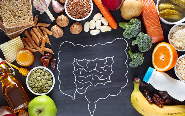Kreidezeichnung eines Darms auf einer Schiefertafel, umgeben von gesunden Lebensmitteln.