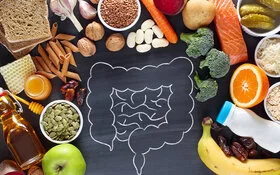 Kreidezeichnung eines Darms auf einer Schiefertafel, umgeben von gesunden Lebensmitteln.